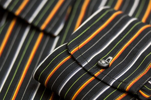 Macro shot showcasing the striped pattern and detailed texture of a men's dress shirt cuff.