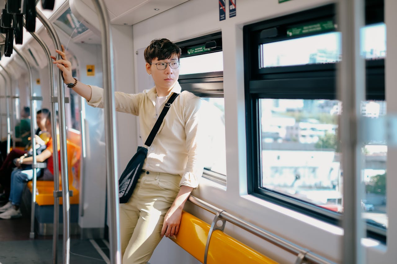 A young man posing stylishly inside a train in Bangkok, Thailand during the day.